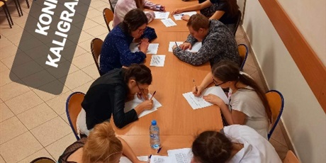 Powiększ grafikę: Przy stole siedzą uczniowie i rozwiązują zadania konkursowe.