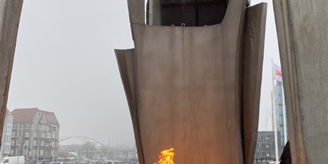 Powiększ grafikę: Palący się znicz wewnątrz pomnika poległych stoczniowców.