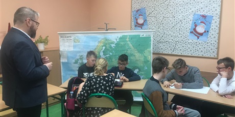 Powiększ grafikę: Uczniowie siedzą w ławkach w drupach i wykonują prace, Pan Arkadiusz Smagacz przygląda się pracy uczniów.